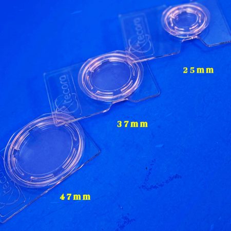 Transparent plastic rings with different inner diameters, labeled 47 mm, 37 mm, and 25 mm on a blue surface. Used as size templates or adapters for lenses.